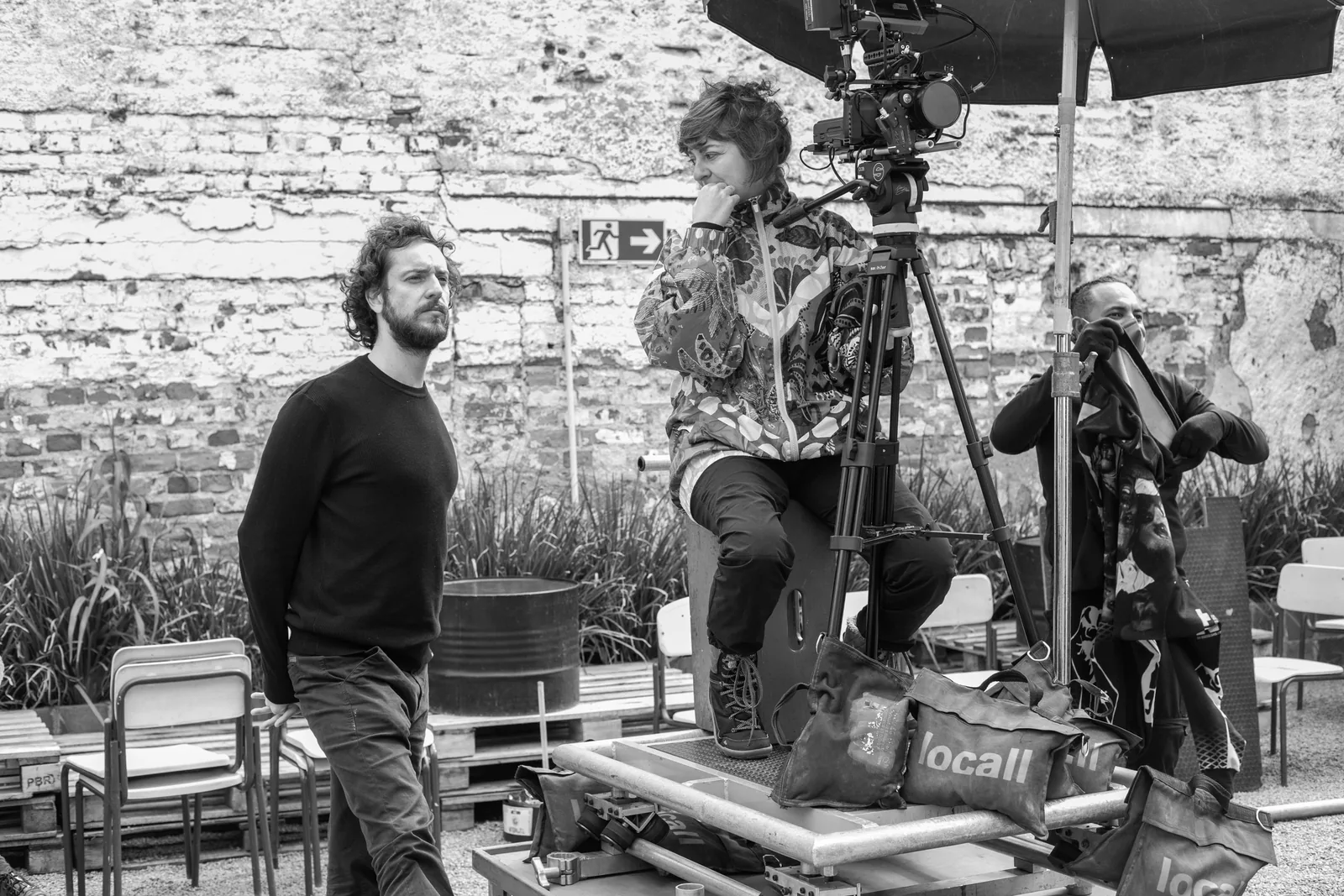 Crew gathered around a camera on a dolly track, in a brick courtyard